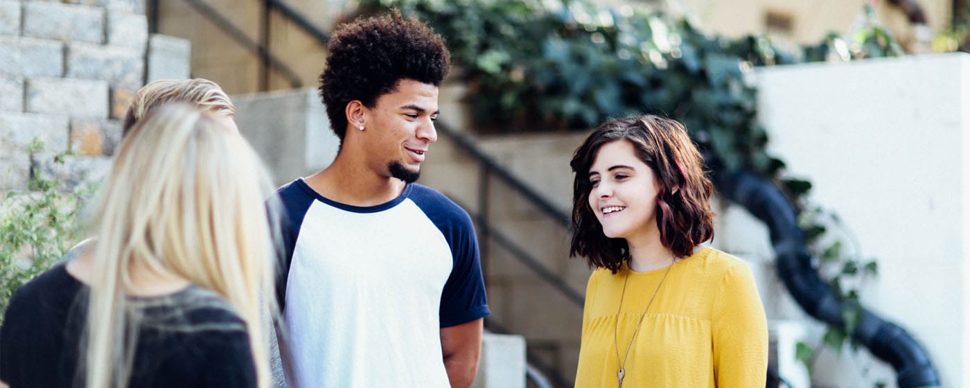 young adults smiling, talking in a group of people