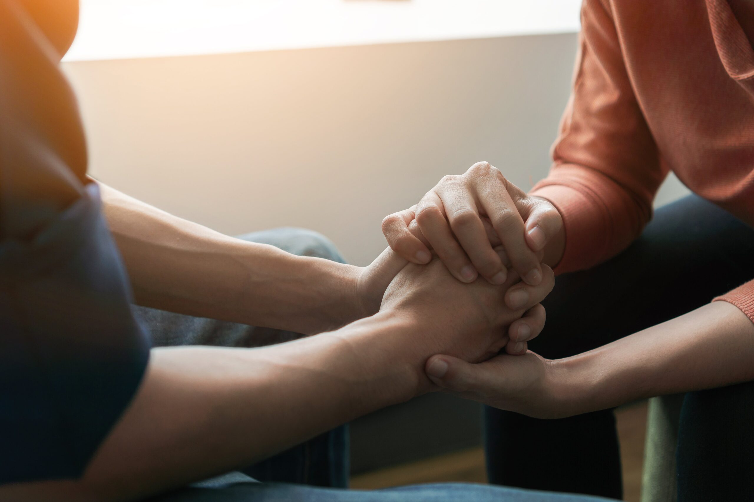 Two people holding hands to support each other.