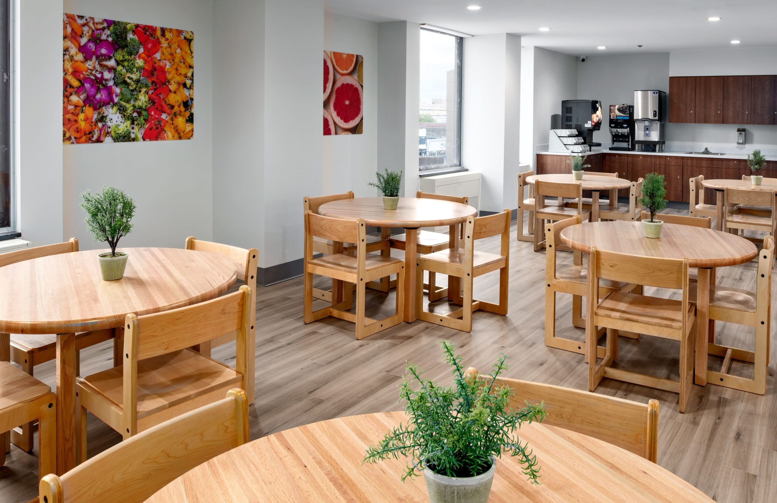 Picture showing Malvern Behavioral Clinic's cafeteria or a waiting room with chairs and tables, beautiful wall hanging, indoor plants on tables and a coffee/tea machine by the wall.