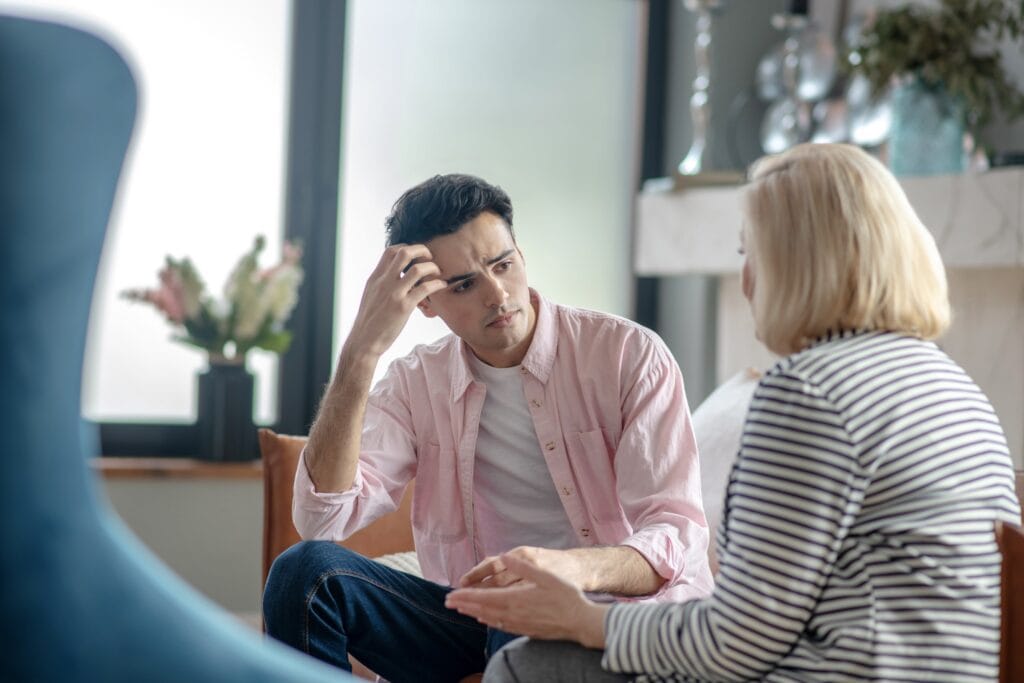 Young adult man talking to his therapist.