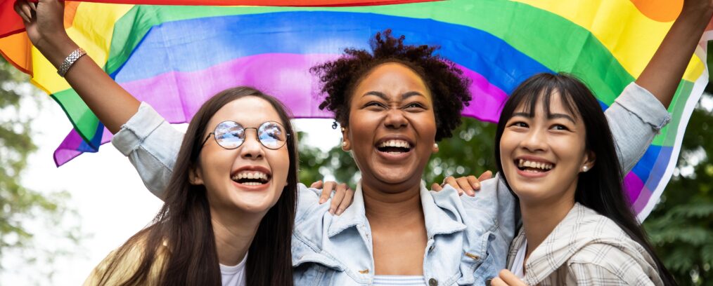 Members of the LGBTQ+ community holding up a Pride flag.