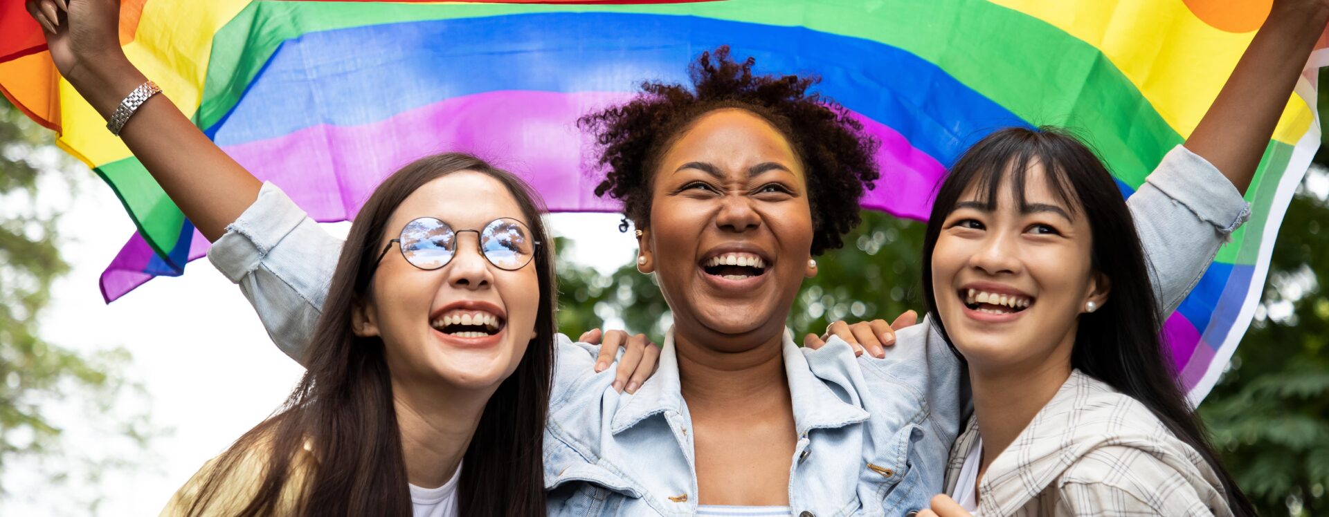 Members of the LGBTQ+ community holding up a Pride flag.
