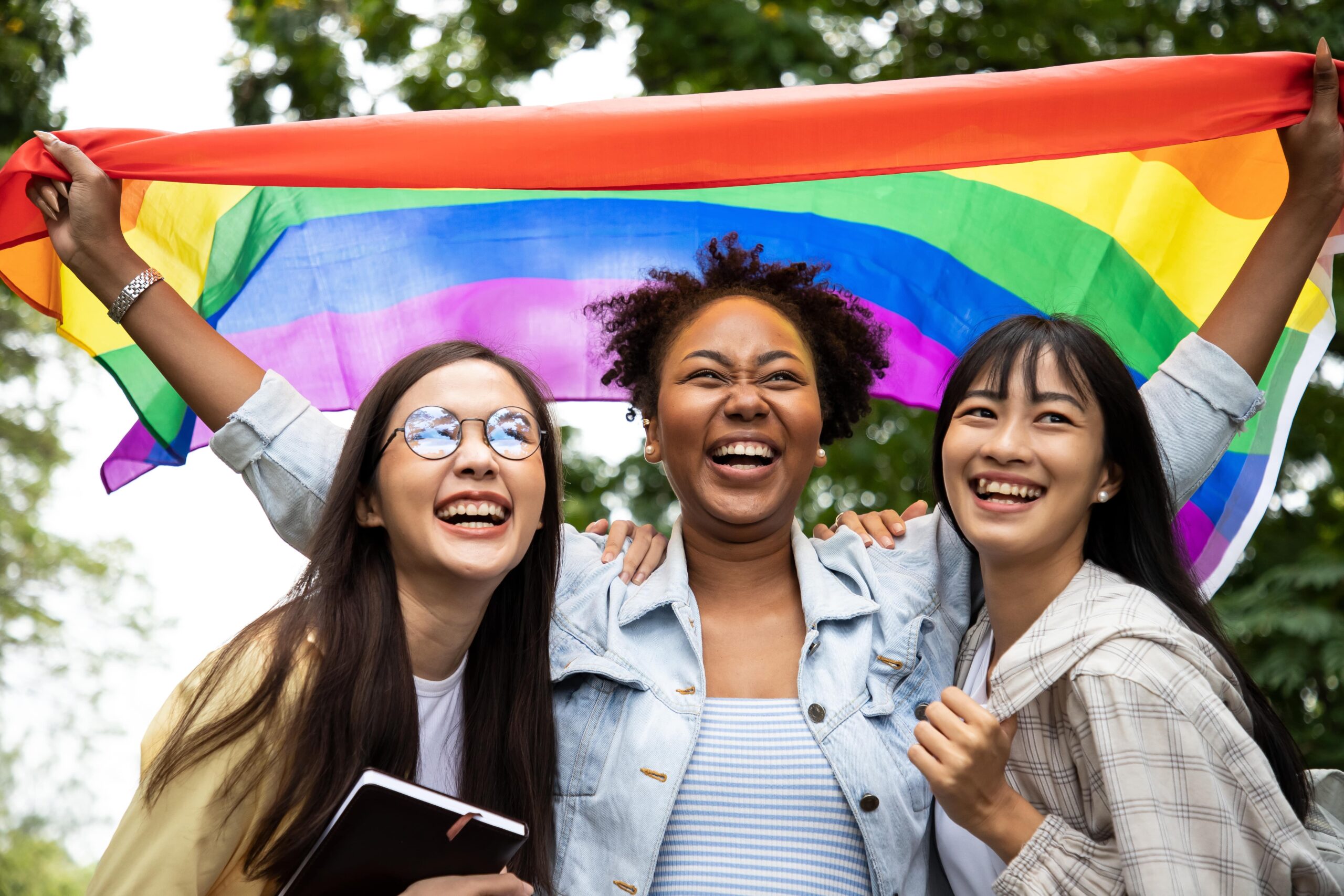 Members of the LGBTQ+ community holding up a Pride flag.