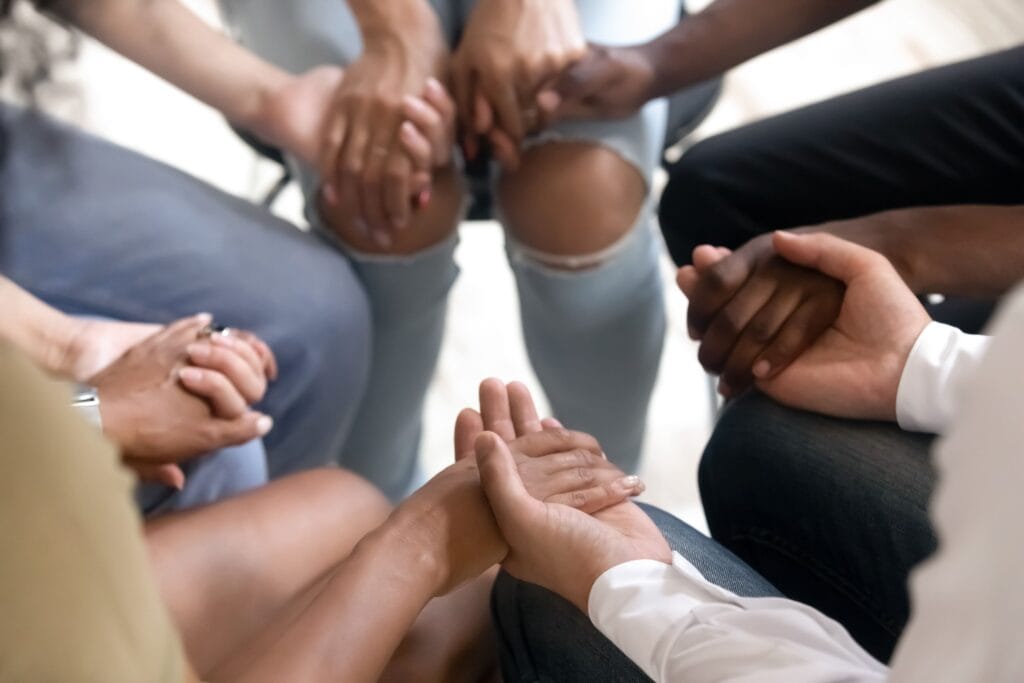 Group of young adults holding hands during a therapy session.