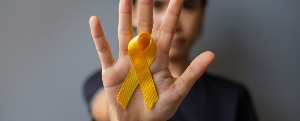 Individual holding up a suicide prevention and awareness ribbon.