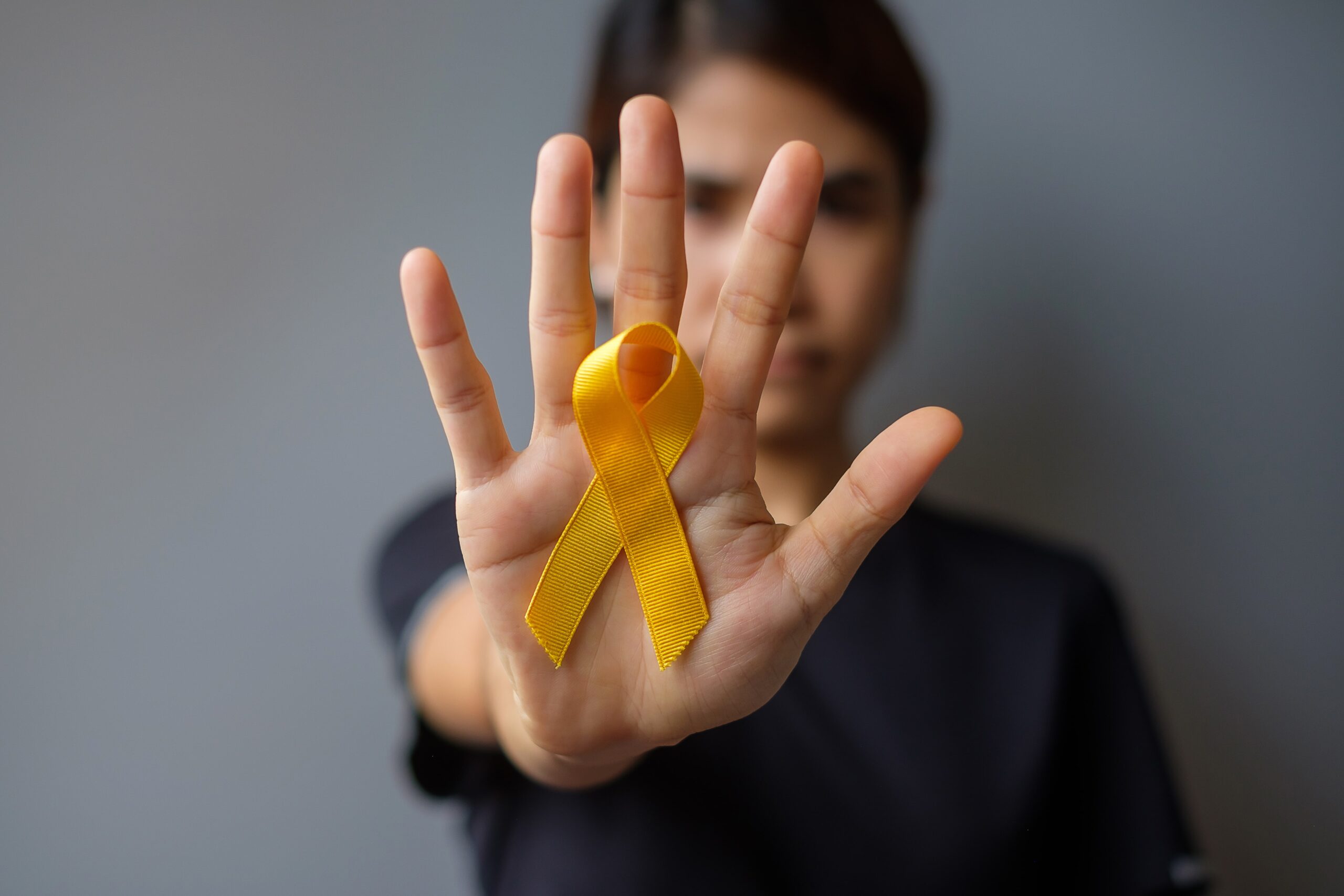 Individual holding up a suicide prevention and awareness ribbon.