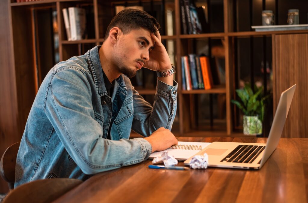 Young man sitting at his desk stressed with work.