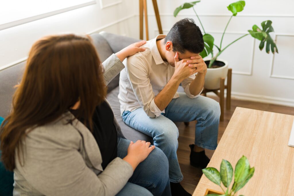 Young adult in therapy being comforted by a mental health professional.