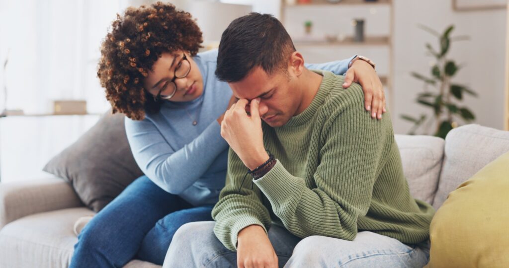 Young adult woman helping young man who is upset.