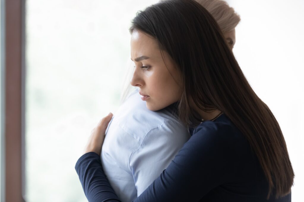 Woman hugging another individual who is dealing with grief after suicide.