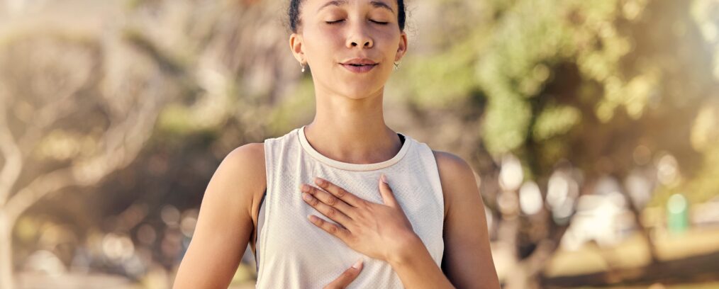 Young adult woman practicing mindfulness breathing while on a walk.