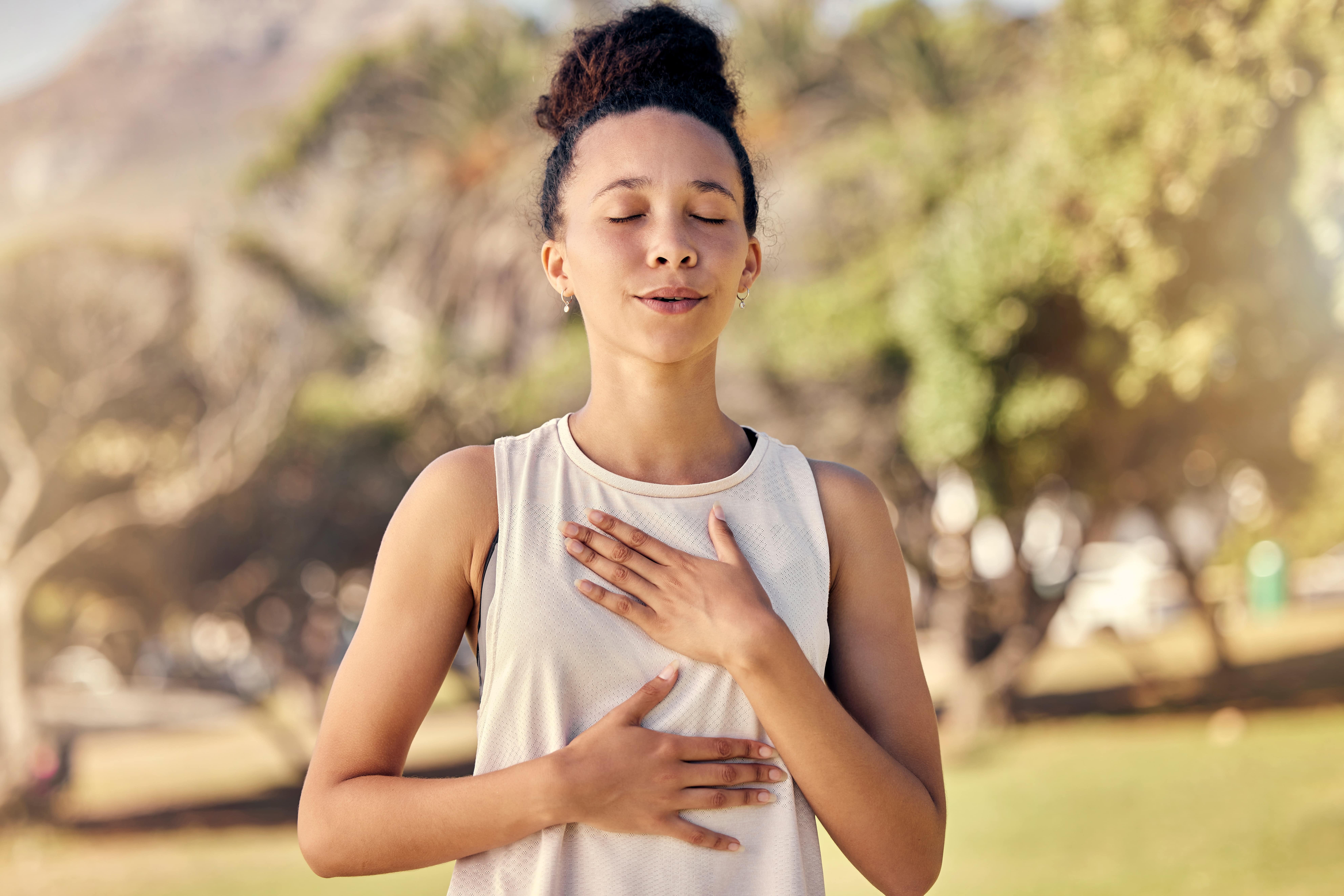 Young adult woman practicing mindfulness breathing while on a walk.