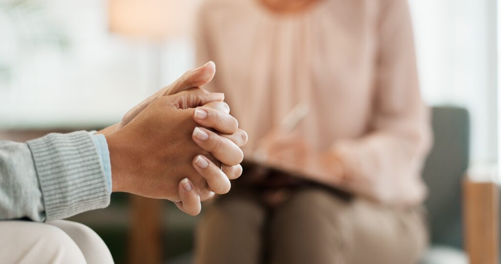 Individual folding hands as they speak to a therapist.