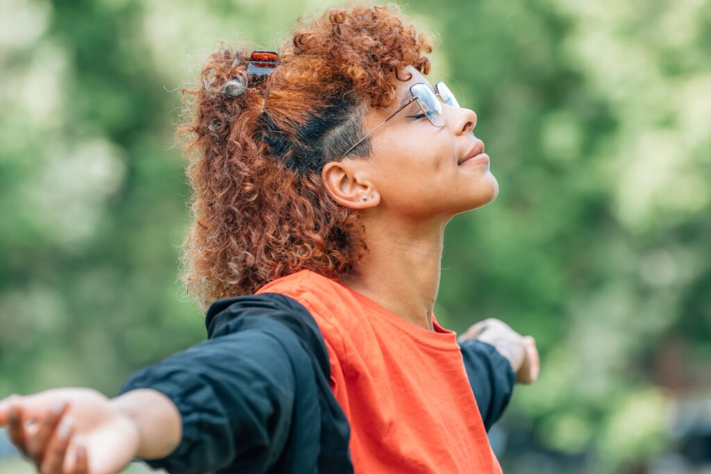 Young adult woman breathing deeply outside.