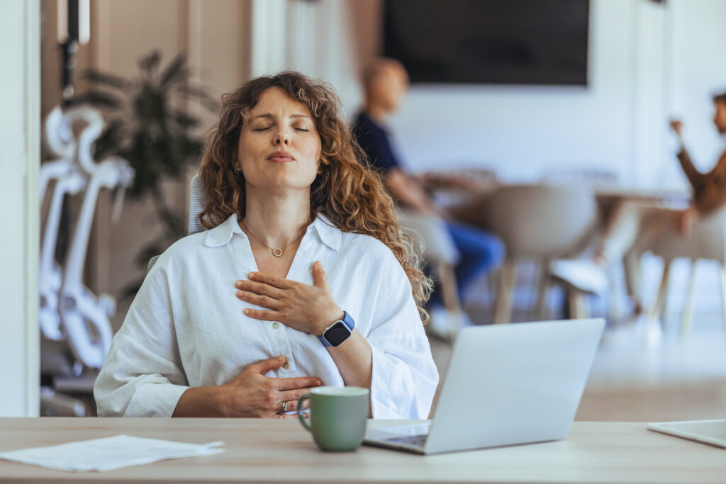 Woman practicing deep breathing exercises at her desk.