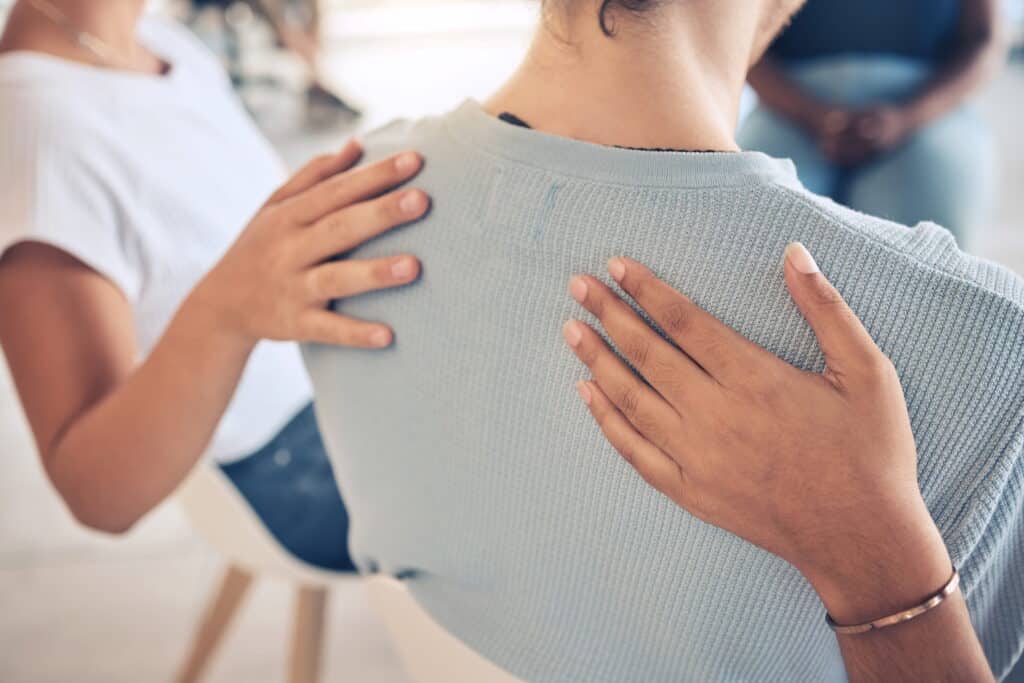 Adults comforting each other in a mental health group therapy session.