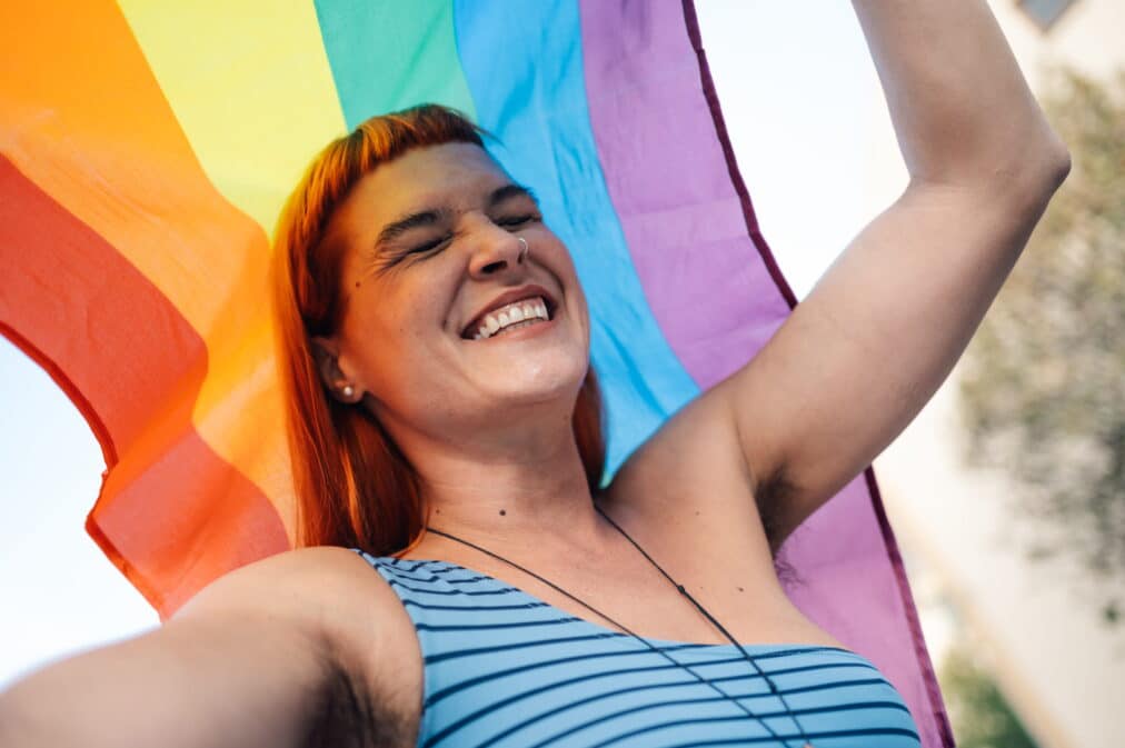 Individual holding a LGBTQIA+ flag.