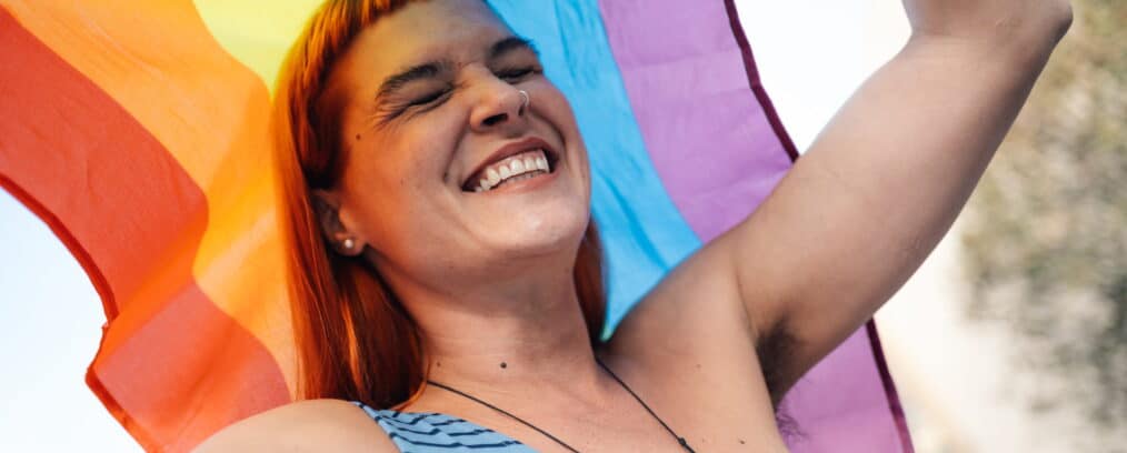 Individual holding a LGBTQIA+ flag.