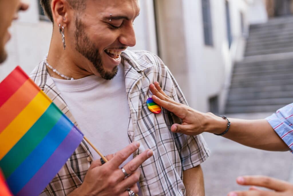 Individual pinning a Pride flag pin onto a friend's shirt.