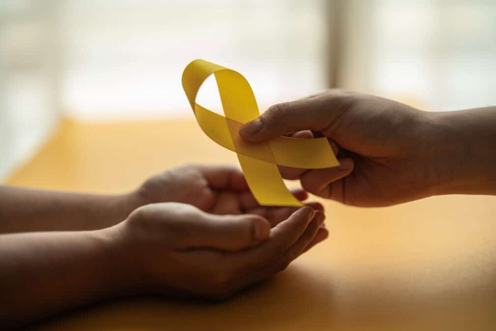 An individual handing someone a suicide prevention awareness ribbon.