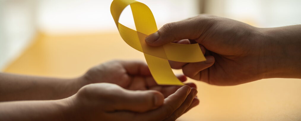 An individual handing someone a suicide prevention awareness ribbon.