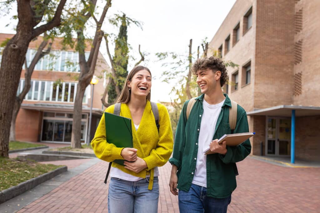 Two students walking on campus talking.
